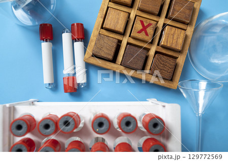 Closeup view of an empty test tube with a wooden tic tac toe game on a blue background. Mockup or Copy space. Concept of healthcare and medicine Closeup view of an empty test tube with a wooden tic tac toe game on a blue background. Mockup or Copy space. Concept of healthcare and medicine 129772569