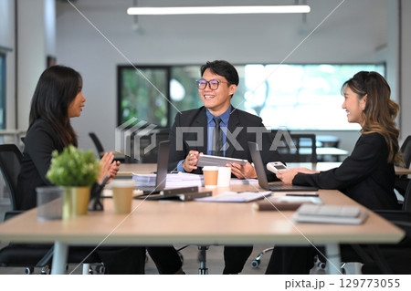 Businesspeople in formal attire sharing ideas and strategies around a meeting table in a bright office 129773055