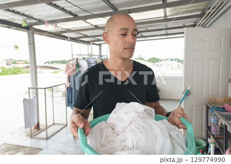Bald Hispanic man in 40s working and washing laundry outdoors Bald Hispanic man in 40s working and washing laundry outdoors 129774990