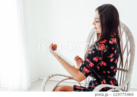 woman with digital tablet sitting in chair at home 129775960