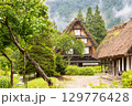 夏の雨に霞む白川郷の合掌造りと木々の風景 129776428