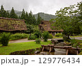 大雨の中、白川郷の古民家と山と川の風景 129776434