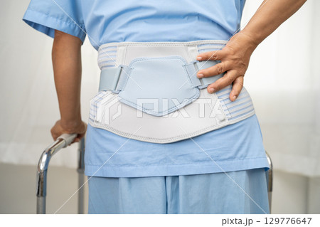 Asian lady patient wearing back pain support belt for orthopedic lumbar with walker. Asian lady patient wearing back pain support belt for orthopedic lumbar with walker. 129776647