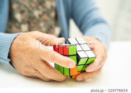 Bangkok, Thailand August 14, 2023 Alzheimer disease AD, Asian elderly woman patient playing Rubik cube game to practice brain training for dementia prevention. Bangkok, Thailand August 14, 2023 Alzheimer disease AD, Asian elderly woman patient playing Rubik cube game to practice brain training for dementia prevention. 129776654