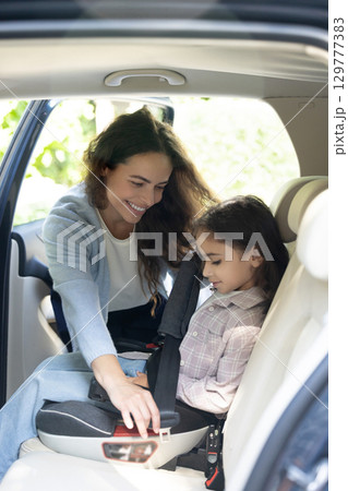 Mom fixing safety belt to her kid while traveling by car Mom fixing safety belt to her kid while traveling by car 129777383