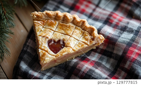 A pie slice with a tiny heart cut into the crust, placed on plaid fabric . A pie slice with a tiny heart cut into the crust, placed on plaid fabric . 129777815