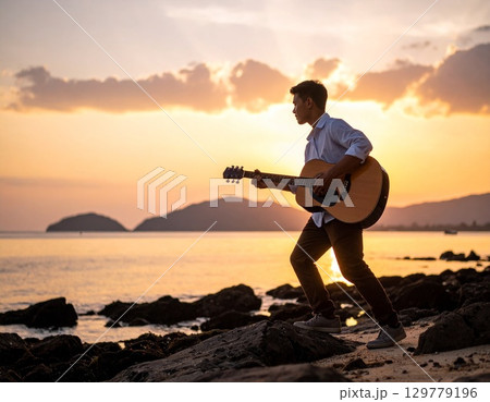 夕暮れの海岸でギターを弾く男性 夕暮れの海岸でギターを弾く男性 129779196