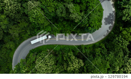 Aerial view semi truck trailer cargo on mountain curve road, Semi truck trailer cargo business logistic transportation on green forest road curve, White semi truck trailer cargo delivery on asphalt Aerial view semi truck trailer cargo on mountain curve road, Semi truck trailer cargo business logistic transportation on green forest road curve, White semi truck trailer cargo delivery on asphalt 129780194