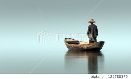 Person in traditional clothing and conical hat standing in a wooden boat on calm water under soft blue sky 129780576