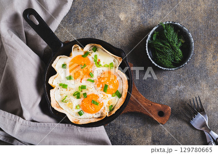 Homemade scrambled eggs in pita bread with herbs in a frying pan on the table top view 129780665