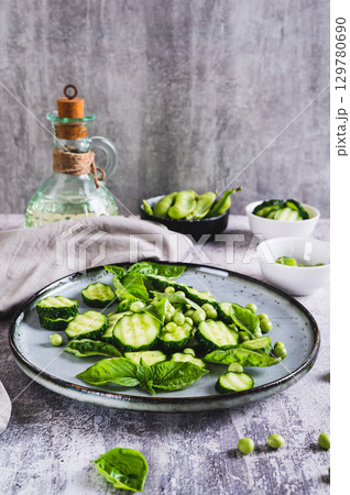 Antioxidant salad of fresh cucumbers, green peas and basil on a plate on the table vertical view 129780690