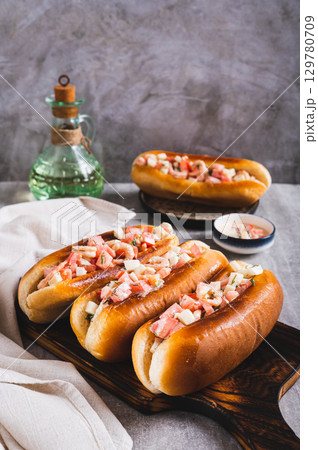 Delicious hot dogs in fried buns with tomato, egg and shrimp salad vertical view Delicious hot dogs in fried buns with tomato, egg and shrimp salad vertical view 129780709