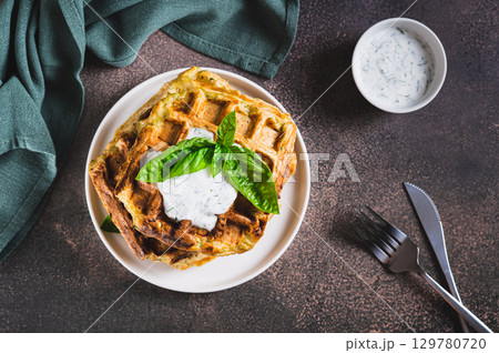 Homemade waffles with sour cream and basil on a plate on the table top view 129780720