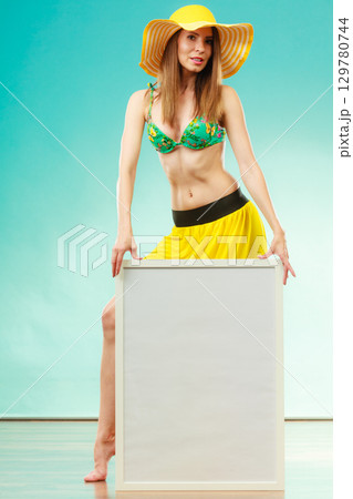 Woman in bikini holds blank presentation board. Woman in bikini holds blank presentation board. 129780744