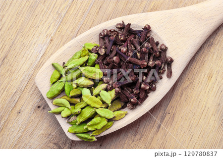 cardamom pods and cloves on wooden spoon 129780837