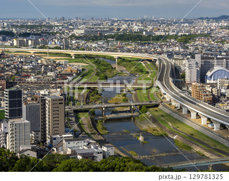 朝日に照らされた川沿いの街並みと橋を渡る電車 129781325