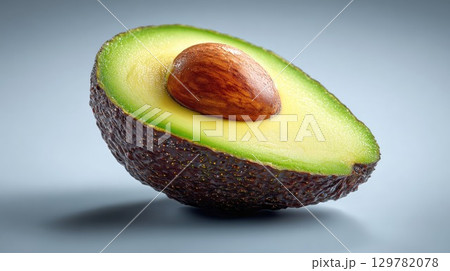 Close-up of a halved avocado, revealing its creamy green flesh and large brown pit against a clean background 129782078