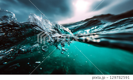 Ocean surface splash with underwater clarity and dramatic lighting from a stormy sky Ocean surface splash with underwater clarity and dramatic lighting from a stormy sky 129782591