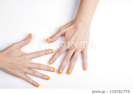 Beautiful woman hands with trendy orange gel polish manicure. Candy corn inspired nail art, stylish nails design, beauty care and fashion details on white background. Halloween Style Beautiful woman hands with trendy orange gel polish manicure. Candy corn inspired nail art, stylish nails design, beauty care and fashion details on white background. Halloween Style 129782759