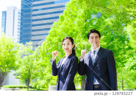 新緑の街でガッツポーズする男女ビジネスパーソンのグループ 129783227