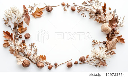 Earthy frame of acorns, oak leaves, and dried flowers on a crisp white background . 129783754