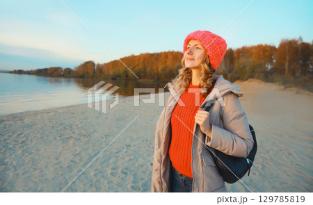 Happy traveler young woman on the beach looking at sunset, enjoying landscape on sea coast Happy traveler young woman on the beach looking at sunset, enjoying landscape on sea coast 129785819