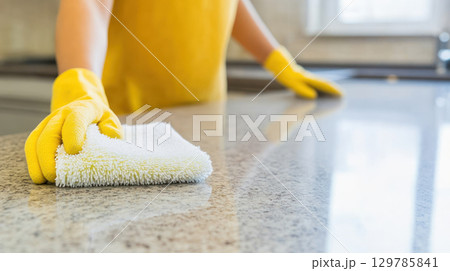 Person cleaning kitchen counter with spray cleaner and microfiber cloth in bright modern kitchen promoting home hygiene and safety Person cleaning kitchen counter with spray cleaner and microfiber cloth in bright modern kitchen promoting home hygiene and safety 129785841