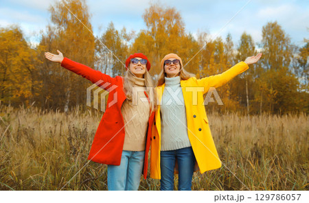 Happy cheerful young two women friends in autumn park, stylish girlfriends smiling together outdoors Happy cheerful young two women friends in autumn park, stylish girlfriends smiling together outdoors 129786057