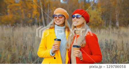 Happy two women friends with autumn yellow leaves in park, stylish smiling girlfriends together Happy two women friends with autumn yellow leaves in park, stylish smiling girlfriends together 129786058