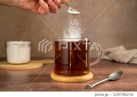 Pouring sweetener powder in cup of tea. Sugar alternative, food and nutrition Pouring sweetener powder in cup of tea. Sugar alternative, food and nutrition 129786216
