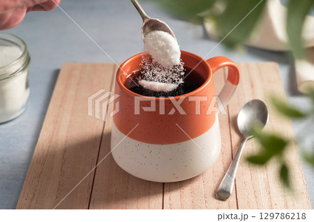 Pouring sweetener powder in cup of coffee. Sugar alternative, food and nutrition 129786218