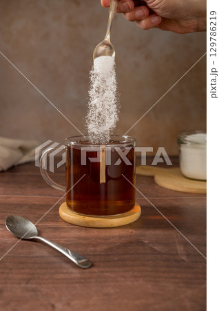 Pouring sweetener powder in cup of tea. Sugar alternative, food and nutrition 129786219