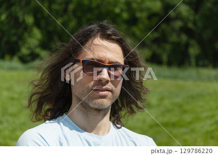 Portrait of glasses brunette man feeling unwell, depression, unhappy at park and green nature setting. 129786220
