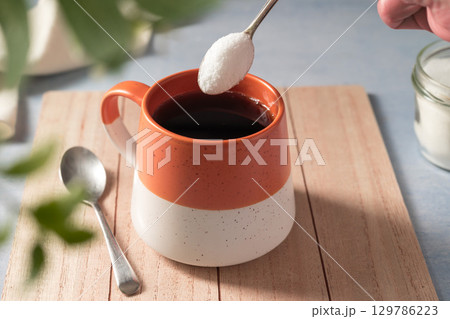 Pouring sweetener powder in cup of coffee. Sugar alternative, food and nutrition 129786223