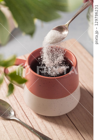 Pouring sweetener powder in cup of tea. Sugar alternative, food and nutrition 129786231