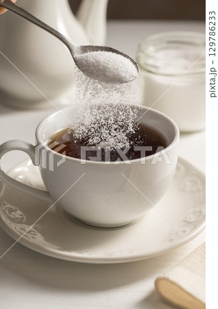 Pouring spoon of sweetener in cup of tea. Sugar alternative, food and nutrition 129786233