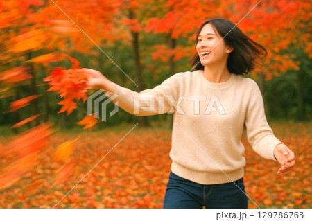 秋の紅葉に包まれる人々の散策　日本の秋を感じる風景素材 129786763