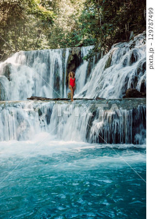 Woman on scenic cascade waterfalls with clear water in Indonesia Woman on scenic cascade waterfalls with clear water in Indonesia 129787499