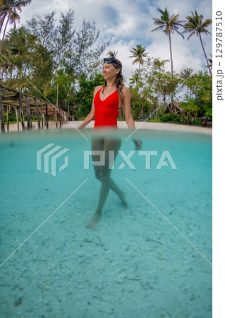 Attractive woman in tropical sea near beach. Vertical split shot 129787510