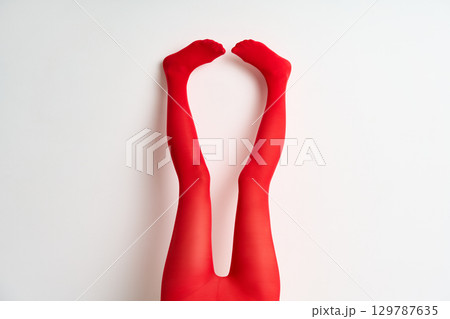female legs in red tights raised up posing over white background 129787635