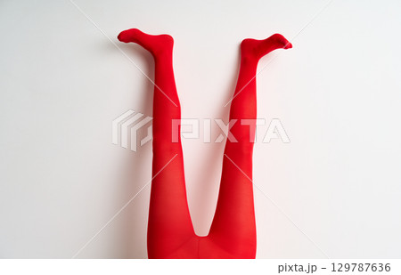 female legs in red tights raised up posing over white background female legs in red tights raised up posing over white background 129787636
