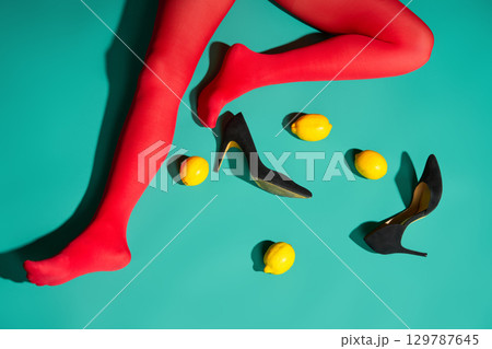 Womans legs in bright red tights and high heels with scattered lemons and purse Womans legs in bright red tights and high heels with scattered lemons and purse 129787645