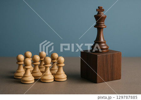 A dark brown king chess piece on a wooden cube with pawns below representing authoritative leadership recognition A dark brown king chess piece on a wooden cube with pawns below representing authoritative leadership recognition 129787885