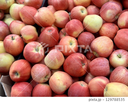 Box filled with fresh juicy natural bio organic red apples placed on counter in local food market. Close-up Box filled with fresh juicy natural bio organic red apples placed on counter in local food market. Close-up 129788535