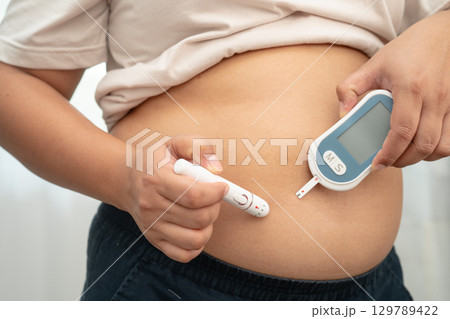 Asian woman injecting herself diabetes injecting insulin in stomach at home. 129789422