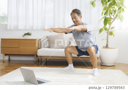 自宅リビングでトレーニングをするシニア男性　宅トレイメージ 129789563