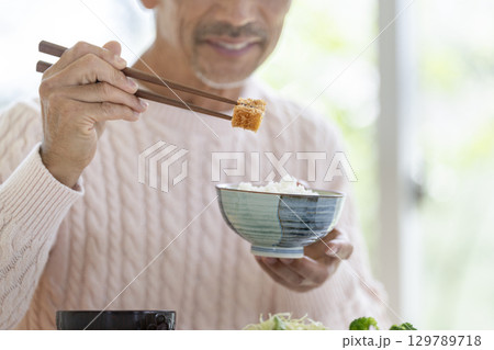 とんかつを食べる60代の男性の手元 129789718