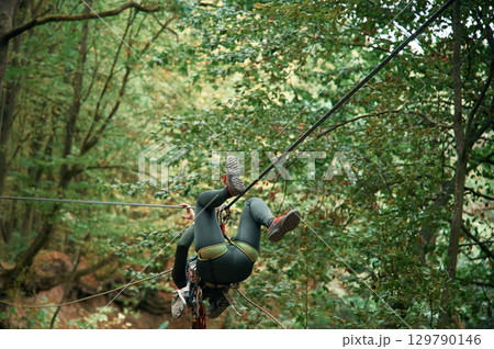 Climbing in the forest. Woman is in the forest using the safety equipment Climbing in the forest. Woman is in the forest using the safety equipment 129790146