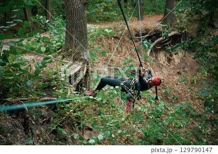 Climbing in the forest. Woman is in the forest using the safety equipment Climbing in the forest. Woman is in the forest using the safety equipment 129790147