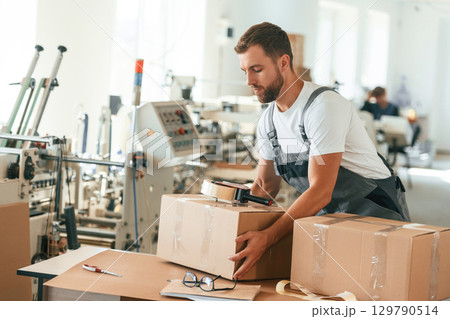 Bunch of eco boxes. Handsome man is working at the factory 129790514